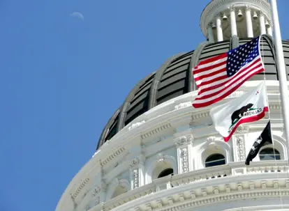 California State Capitol building dome with state flag representing Assembly Bill AB 692 stay-or-pay employment law updates.