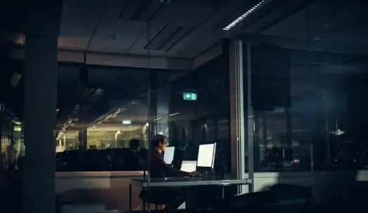 Employee working late overtime hours at a computer in an office, illustrating FLSA overtime pay and tax reporting rules.