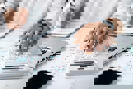 working on calculator, laptop and paperwork